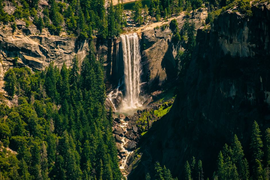 Stunning waterfall cascading down a cliff in Yosemite Valley, surrounded by lush greenery.